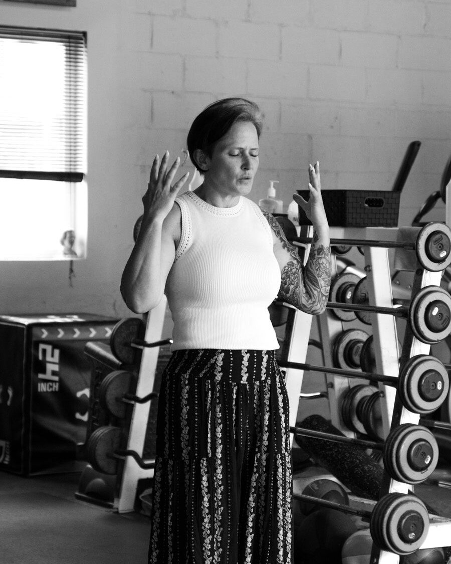 Kari Pennington leading a session, hands raised and eyes closed as she demonstrates a breathing drill