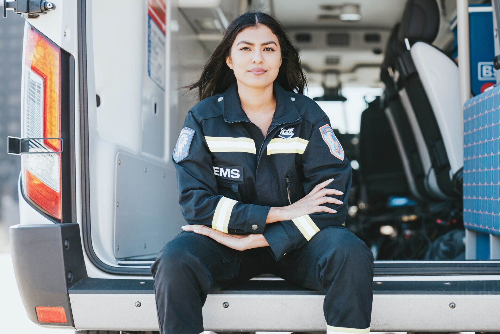 A paramedic sits in the open back of an ambulance